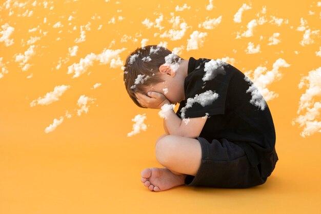 Niño cuya depresión está sentada en el suelo de color