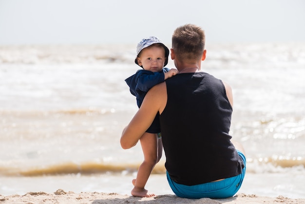 Niño da abrazos a joven en la playa del mar