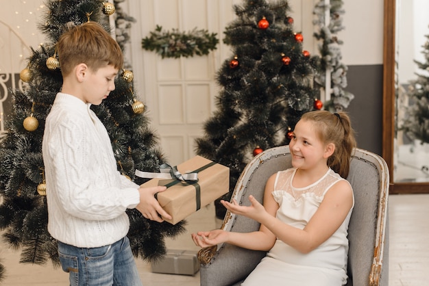 Niño le da a una linda niña un regalo de Navidad