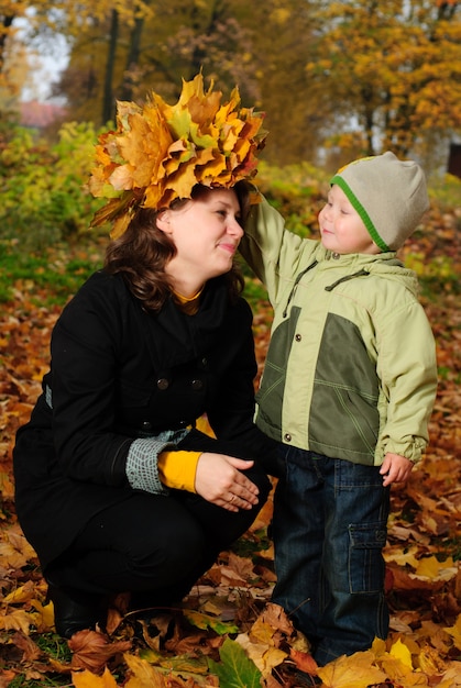 Niño le da a su madre la guirnalda de hojas de otoño de arce. Familia feliz