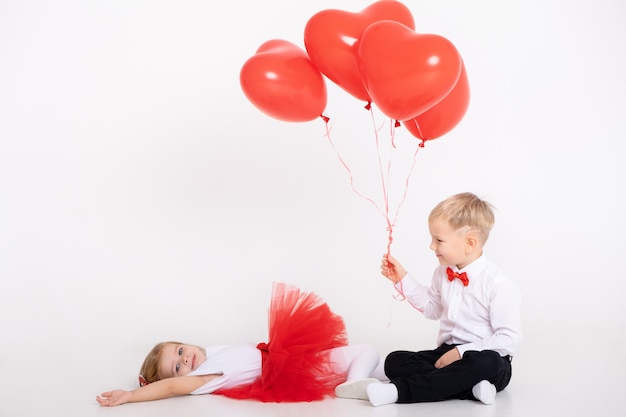 Niño dando globos de corazón a niña pequeña en el día de San Valentín