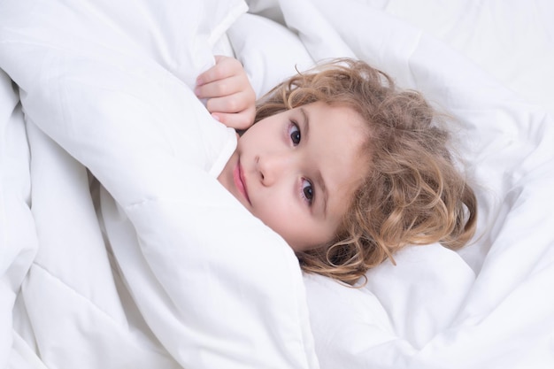 Niño debajo de la cubierta de la cara cubierta con una manta durmiendo tranquilamente retrato de un niño pequeño acostado en una cama grande