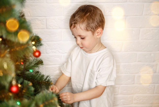 Niño decorar el árbol de navidad en casa niño en vísperas de navidad