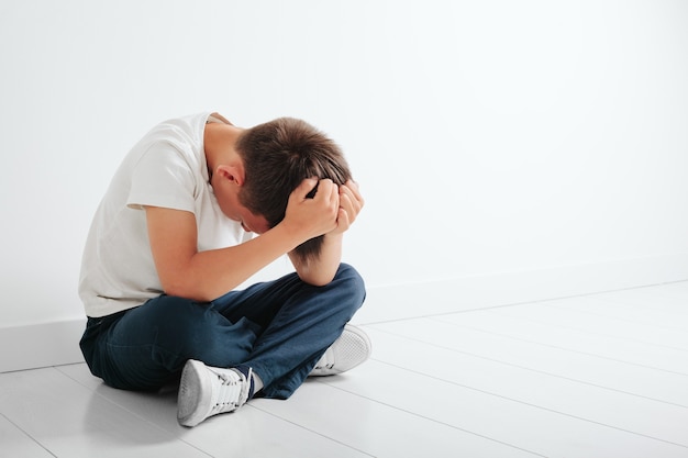 Un niño con depresión está sentado en el suelo.