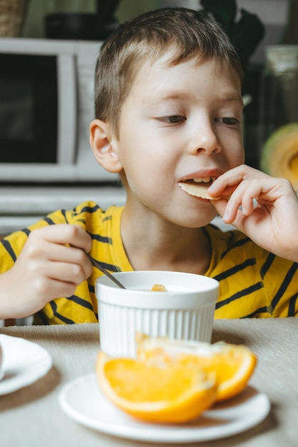 Foto el niño desayuna por la mañana con cereales con leche desayuno matutino en la cocina