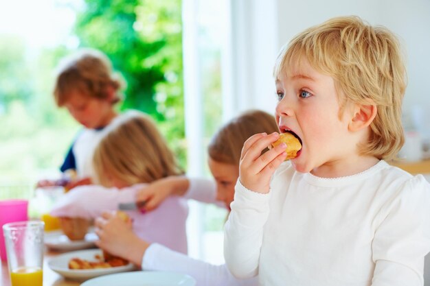 Niño desayunando con su familia en segundo plano Retrato de un niño pequeño desayunando con su familia en segundo plano