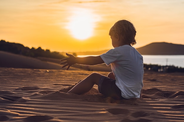 El niño en el desierto rojo al amanecer. Viajar con el concepto de niños.