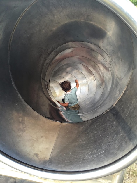Foto niño deslizándose por un túnel metálico