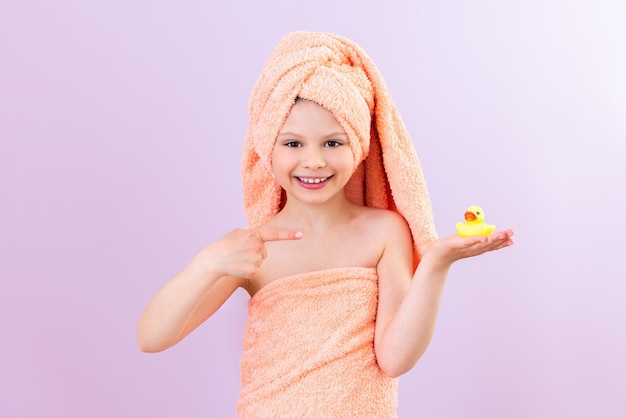 Un niño después de una ducha Una niña envuelta en una toalla después de bañarse sostiene un pato para bañarse