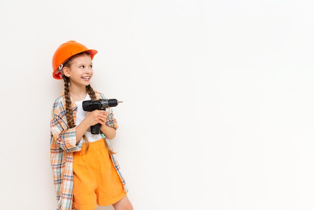 Un niño con un destornillador y un casco de seguridad de construcción sobre un fondo blanco aislado mira y muestra su anuncio El concepto de renovación en la habitación de los niños