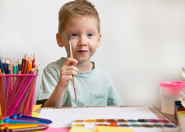 El niño dibuja con un pincel y pinta sobre papel Acuarela para dibujar Niño artista en la escuela