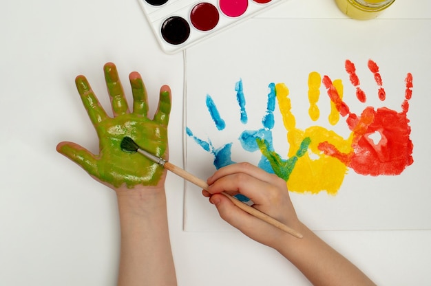 El niño dibuja su mano con pintura verde y un pincel Pintar con los dedos o arteterapia para niños Actividades divertidas para niños