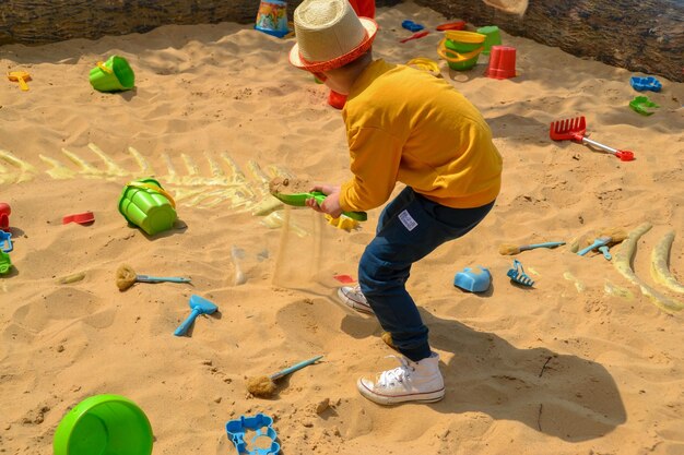 Un niño dibujando en la arena con tiza.