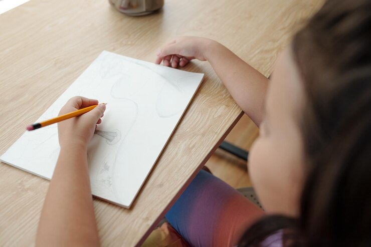 Foto un niño dibujando en un cuaderno de bocetos