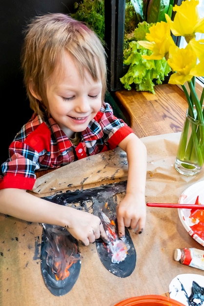 Niño dibujando las orejas de un conejito de Pascua hecho a mano de cartón Preparación para la celebración de las vacaciones de Pascua