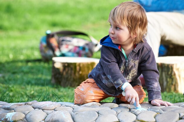 Niño dibujando con tiza en el parque.