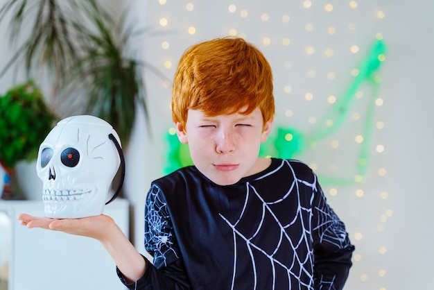 Niño con disfraz de araña esqueleto sosteniendo una canasta de Halloween con forma de calavera