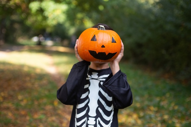 niño disfrazado de esqueleto con una calabaza en la fiesta de Halloween