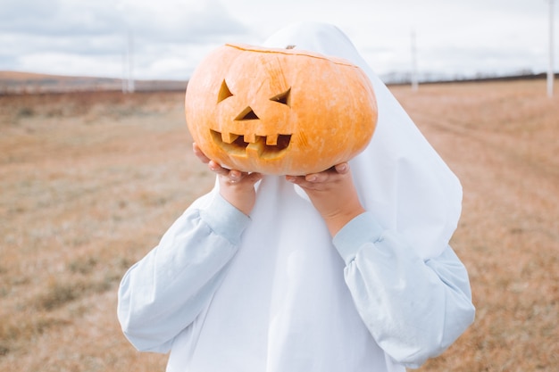 Niño disfrazado de Halloween con calabaza tallada. Truco o trato de Halloween.