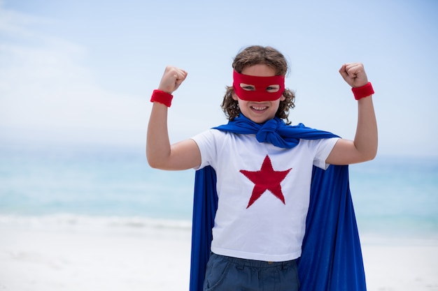 Niño disfrazado de superhéroe apretando el puño en la playa