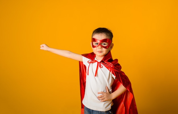 Niño disfrazado de superhéroe sobre una superficie amarilla con espacio para texto