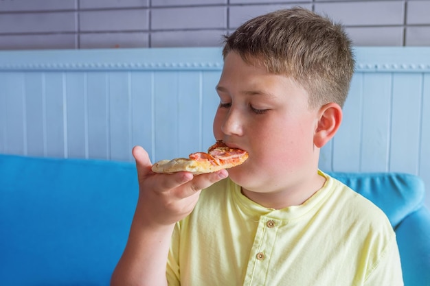 El niño disfruta comiendo pizza Concepto Obesidad y dieta poco saludable