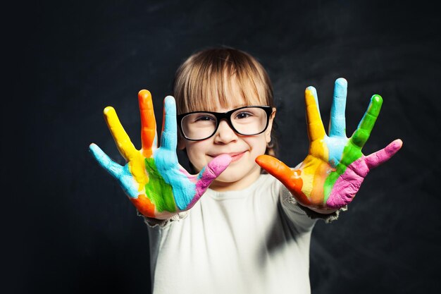 Foto niño disfrutando de su pintura niña linda con manos coloridas en el fondo de la pizarra de la clase artes y concepto de educación creativa