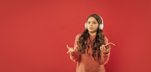 Niño disgustado con suéter escucha música en auriculares con tecnología espacial de copia de teléfono