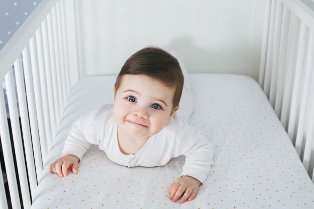 Niño divertido acostado en la cama del bebé y riendo