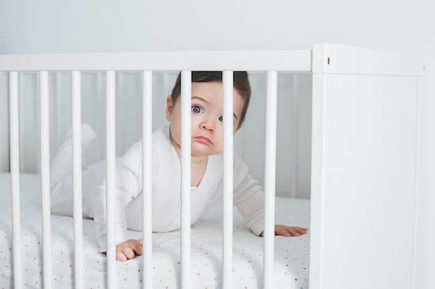 Niño divertido acostado en la cama del bebé