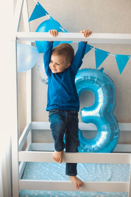 Niño divertido activo en una acogedora casa de cama en la habitación de los niños decorada con globos durante 3 años