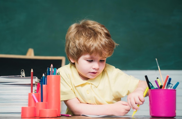 Niño divertido divirtiéndose en el fondo de la pizarra Alumno de la escuela primaria en el patio de la escuela Escuela de niños Escuela de niños Proceso educativo