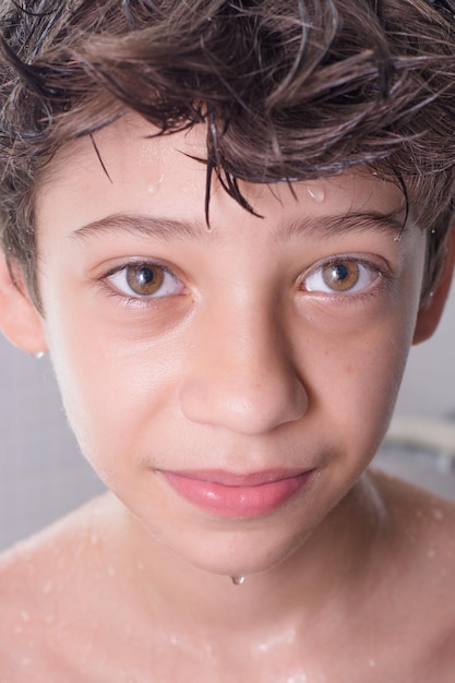 Foto un niño divertido y feliz disfrutando de su baño mientras está bajo el agua corriente