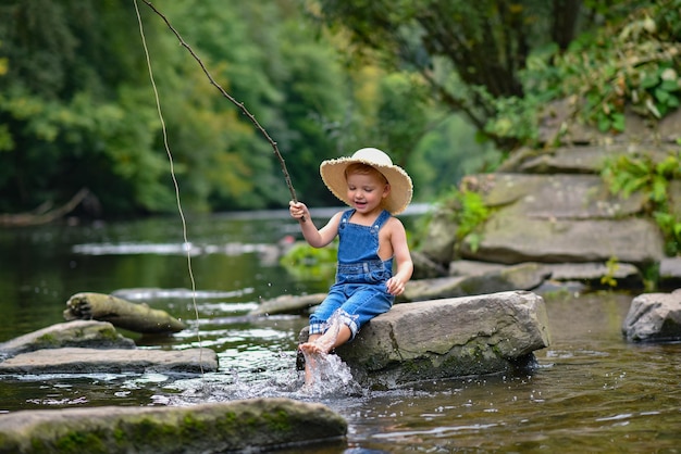 Un niño divertido y feliz pescando en el lago Un niño pescador se sienta en el lago con una caña de pescar