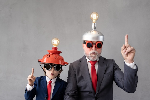 Niño divertido y hombre mayor pretenden ser empresarios. Abuelo y niño jugando en casa. Educación, puesta en marcha y concepto de idea de negocio.