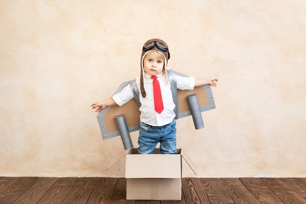 Niño divertido con jet pack de cartón de juguete