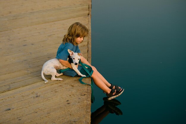 Niño divertido jugando con su cachorro en el parque cerca del lago Infancia despreocupada Protección de animales domésticos