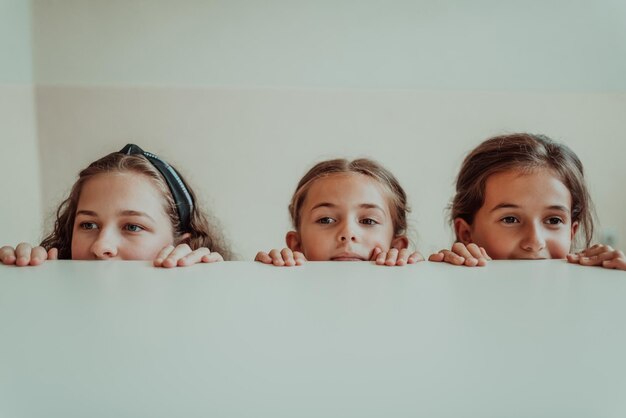 Niño divertido mirando mientras se esconde detrás de una mesa Concepto de regreso a la escuela Enfoque selectivo Foto de alta calidad