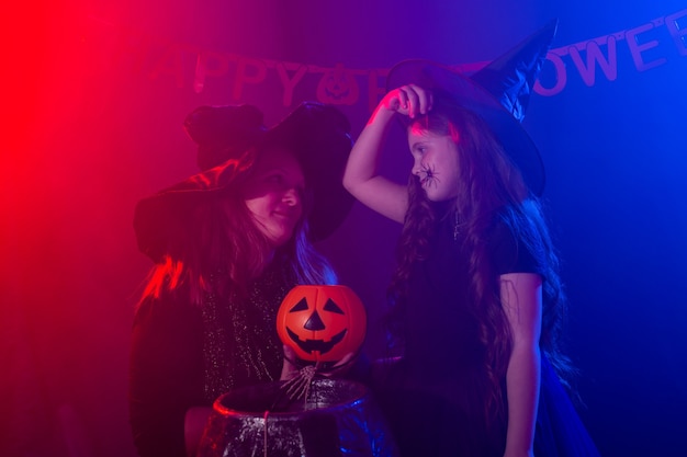Niño divertido niña y mujer en disfraces de brujas para halloween con calabaza jack