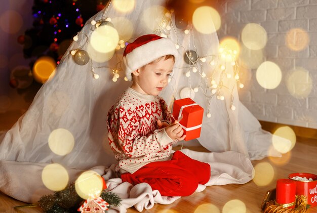 Niño divertido con regalo mágico en casa familia disfrutando de la Navidad