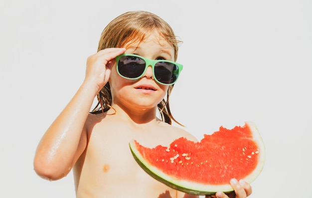 Niño divertido con sandía Niño divirtiéndose en la piscina Vacaciones de verano y alimentación saludable