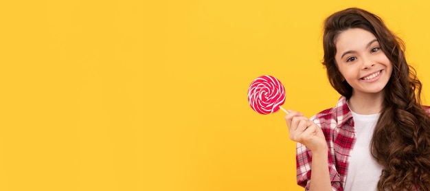 Niño divertido sostener piruleta caramelo caramelo sobre fondo amarillo mostrar gesto de paz Niño adolescente con dulces cartel banner encabezado copia espacio