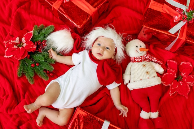 Un niño divertido con un traje de Santa miente en rojo