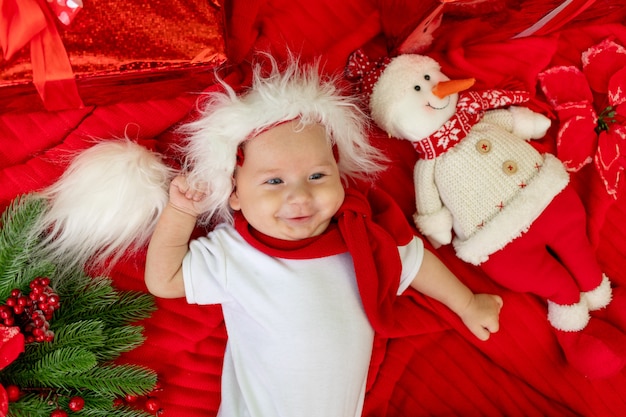 Un niño divertido con un traje de Santa miente en rojo