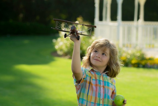 Niño divirtiéndose con avión de juguete en el campo Niño piloto aviador con avión sueña con viajar en verano en la naturaleza