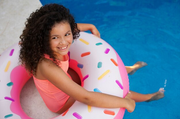 Foto niño divirtiéndose con flotador junto a la piscina