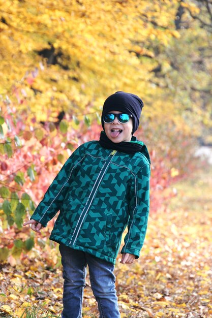 Niño divirtiéndose en el hermoso parque con hojas secas amarillas y rojas. Paseo familiar de otoño en el bosque.