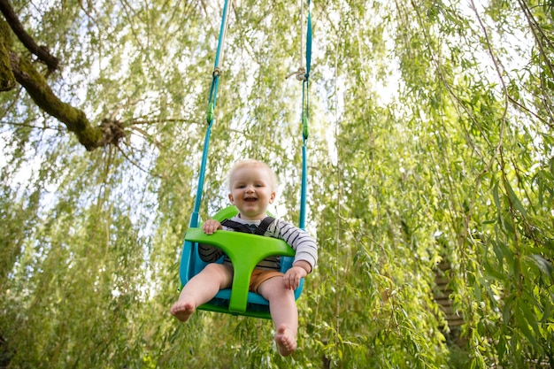 Un niño divirtiéndose jugando en un columpio bajo un árbol en un jardín.