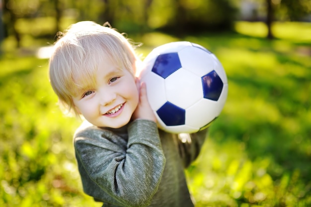 Niño divirtiéndose jugando un partido de fútbol en un día soleado de verano