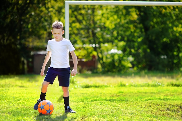 Niño divirtiéndose jugando un partido de fútbol en un día soleado de verano